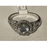 AN 18 CARAT WHITE GOLD RING WITH A CENTRAL 1.03CT SURROUNDED BY SMALL DIAMONDS MADE UP TO 0.30CT