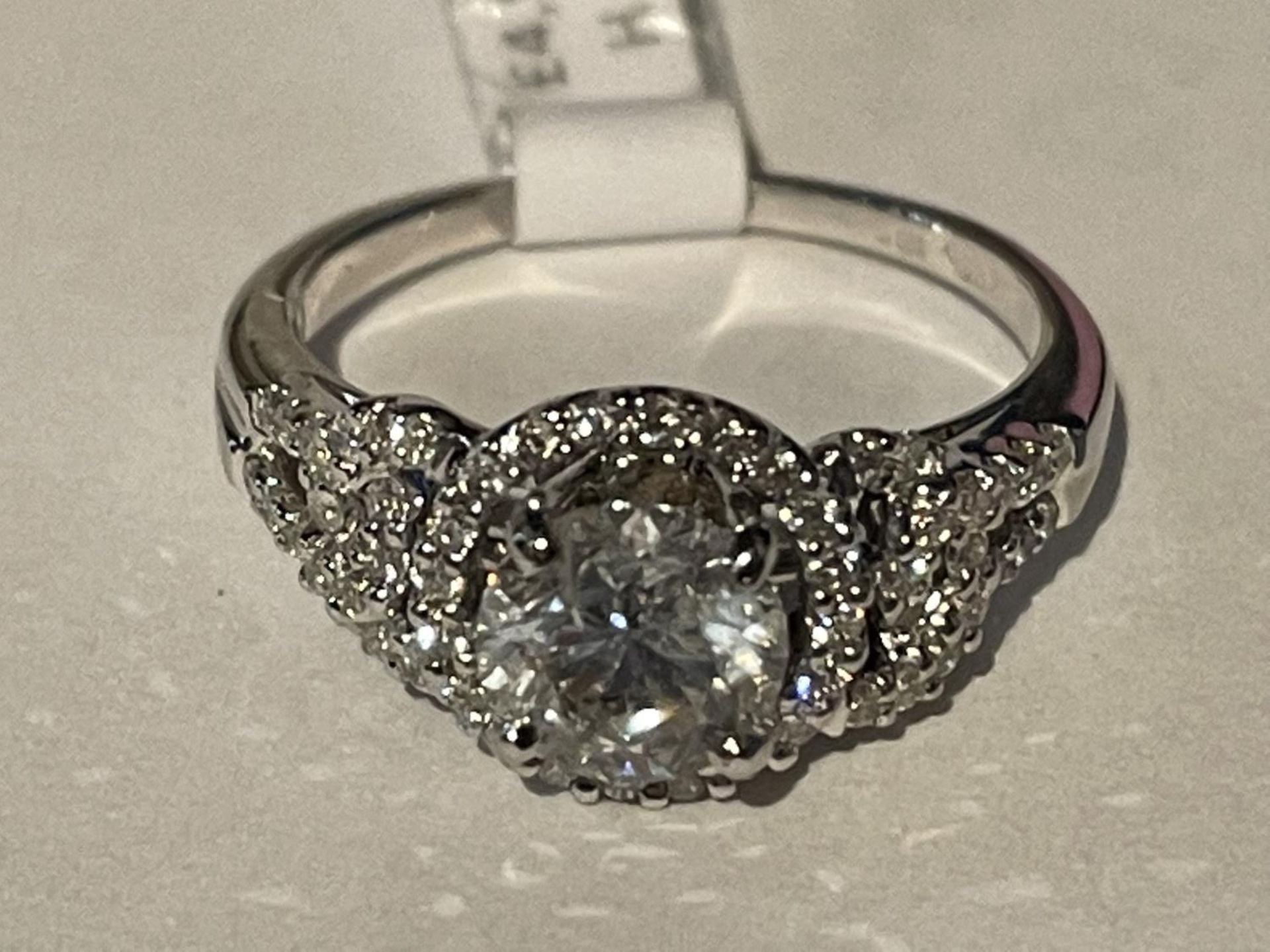 AN 18 CARAT WHITE GOLD RING WITH A CENTRAL 1.03CT SURROUNDED BY SMALL DIAMONDS MADE UP TO 0.30CT