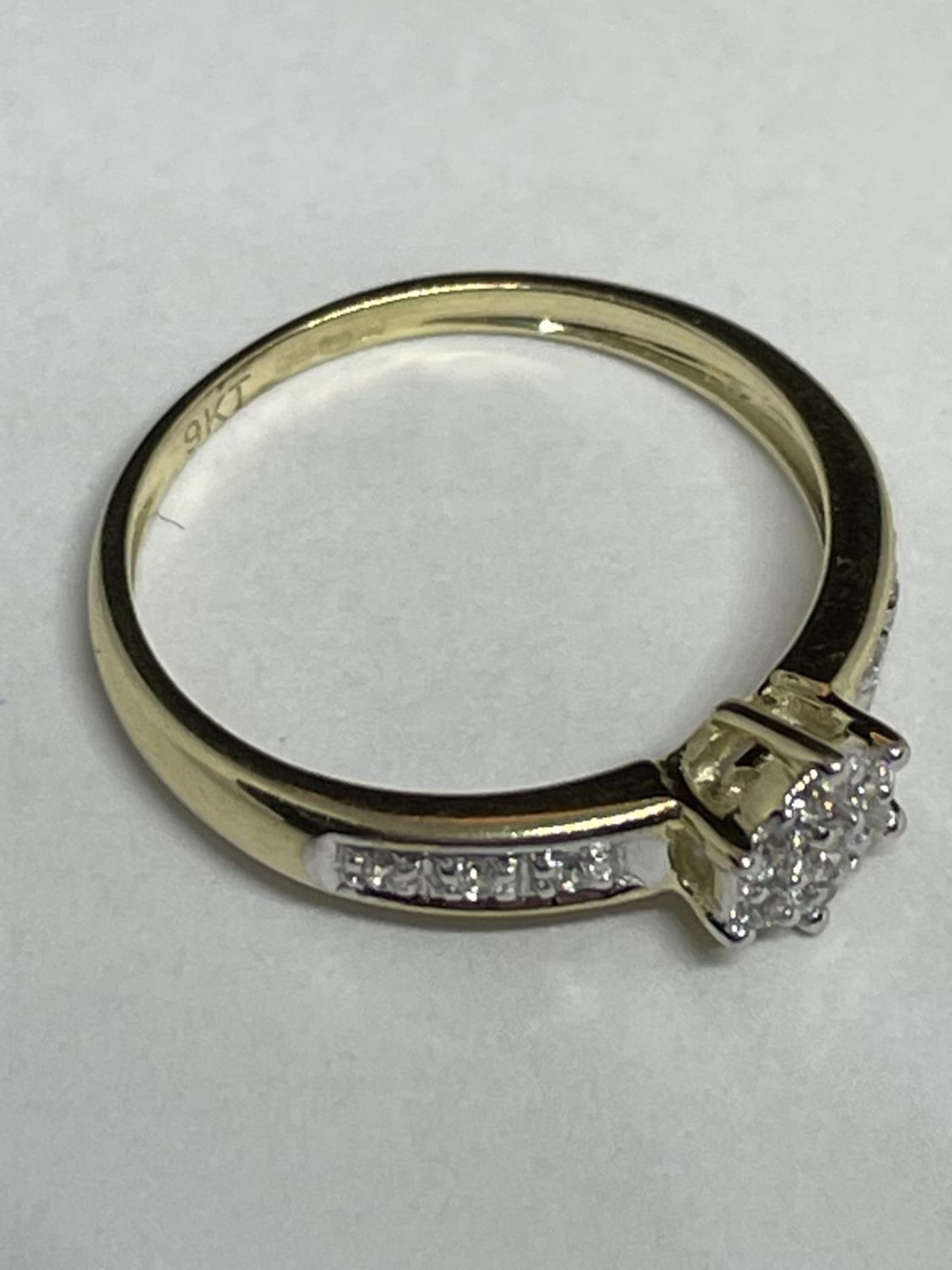 A 9 CARAT GOLD RING WITH CLEAR STONES IN A STAR DESIGN AND ON THE SHOULDERS SIZE J - Image 4 of 4