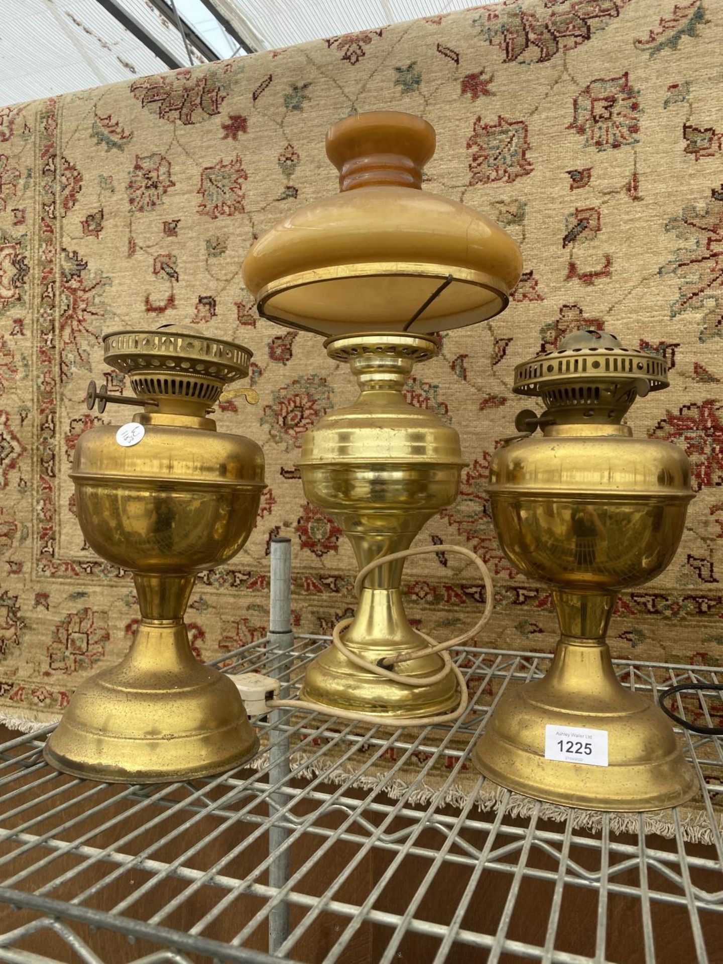 THREE VINTAGE BRASS OIL LAMPS TO INCLUDE ONE CONVERTED TO ELECTRIC WITH A GLASS SHADE