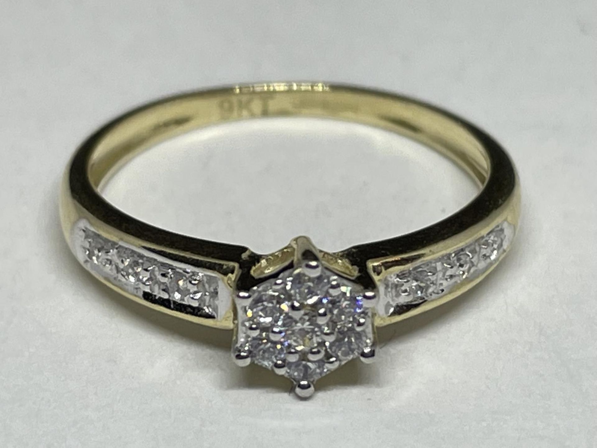 A 9 CARAT GOLD RING WITH CLEAR STONES IN A STAR DESIGN AND ON THE SHOULDERS SIZE J