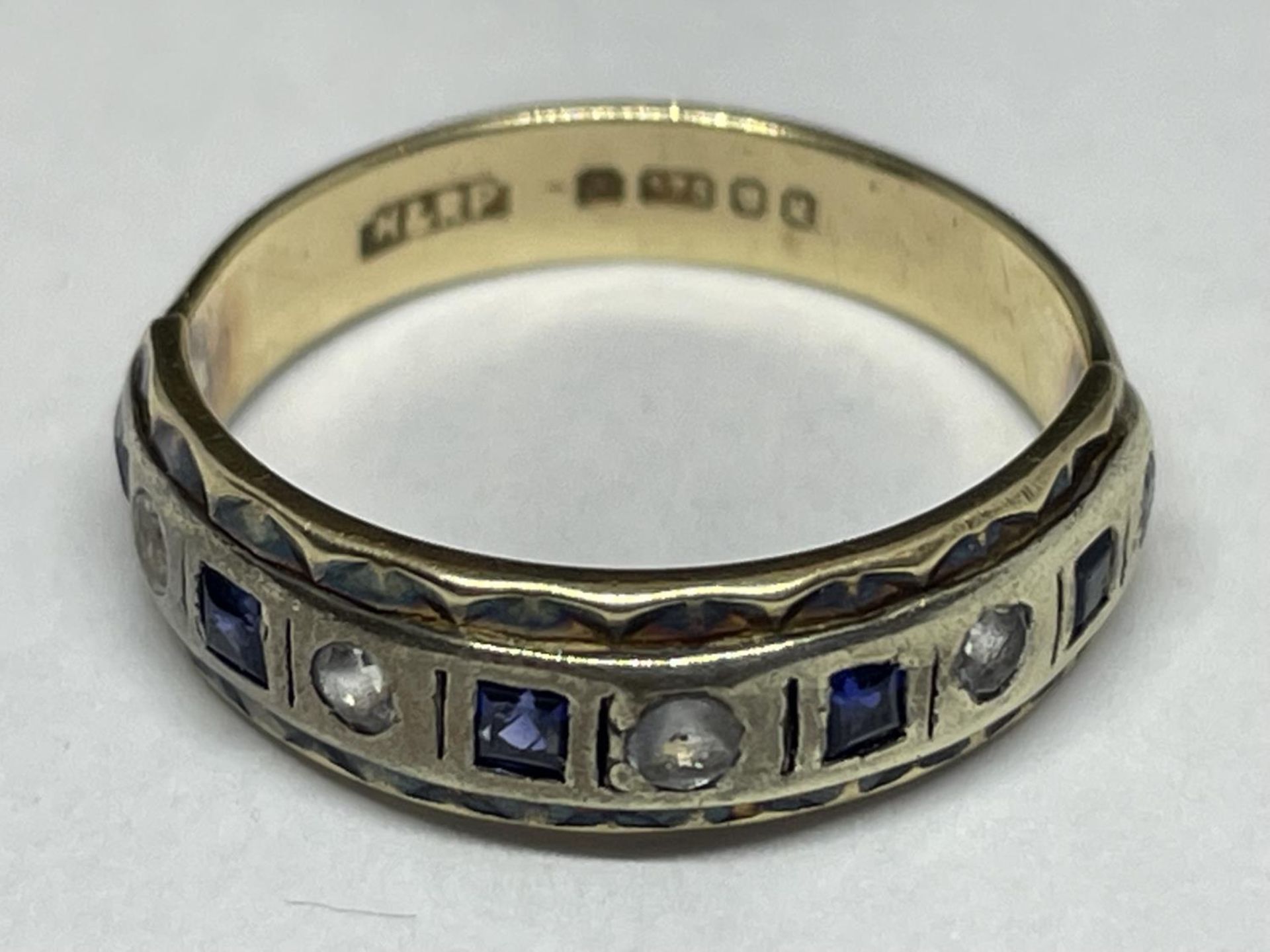 A 9 CARAT GOLD RING WITH FIVE SQUARE SAPPHIRES AND FIVE CLEAR STONES IN A BAND SIZE K