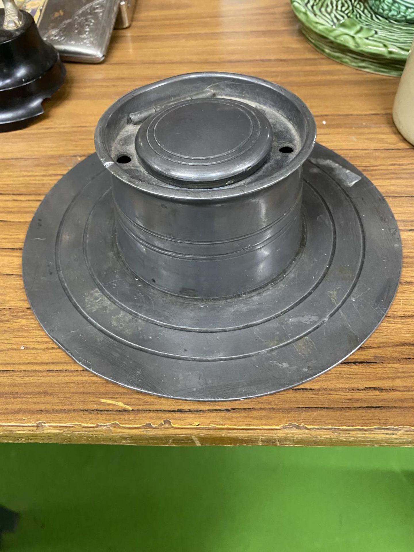 A PEWTER INKWELL ON A PEWTER BASE - MISSING IT'S LINER