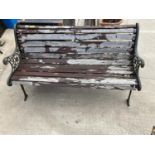 A WOODEN SLATTED GARDEN BENCH WITH DECORATIVE CAST BENCH ENDS