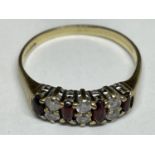 A 9 CARAT GOLD RING WITH FOUR RED STONES AND SIX CLEAR STONES IN A BAND SIZE M