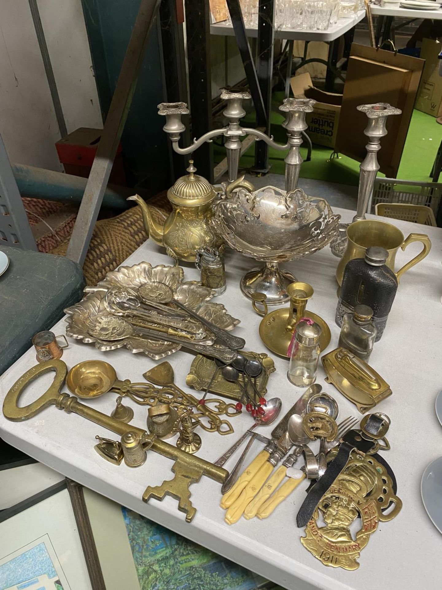 A LARGE AMMOUNT OF BRASS AND SILVER PLATE TO INCLUDE CANDLESTICKS, TAZZA DISH, FLATWARE, HIP FLASKS,