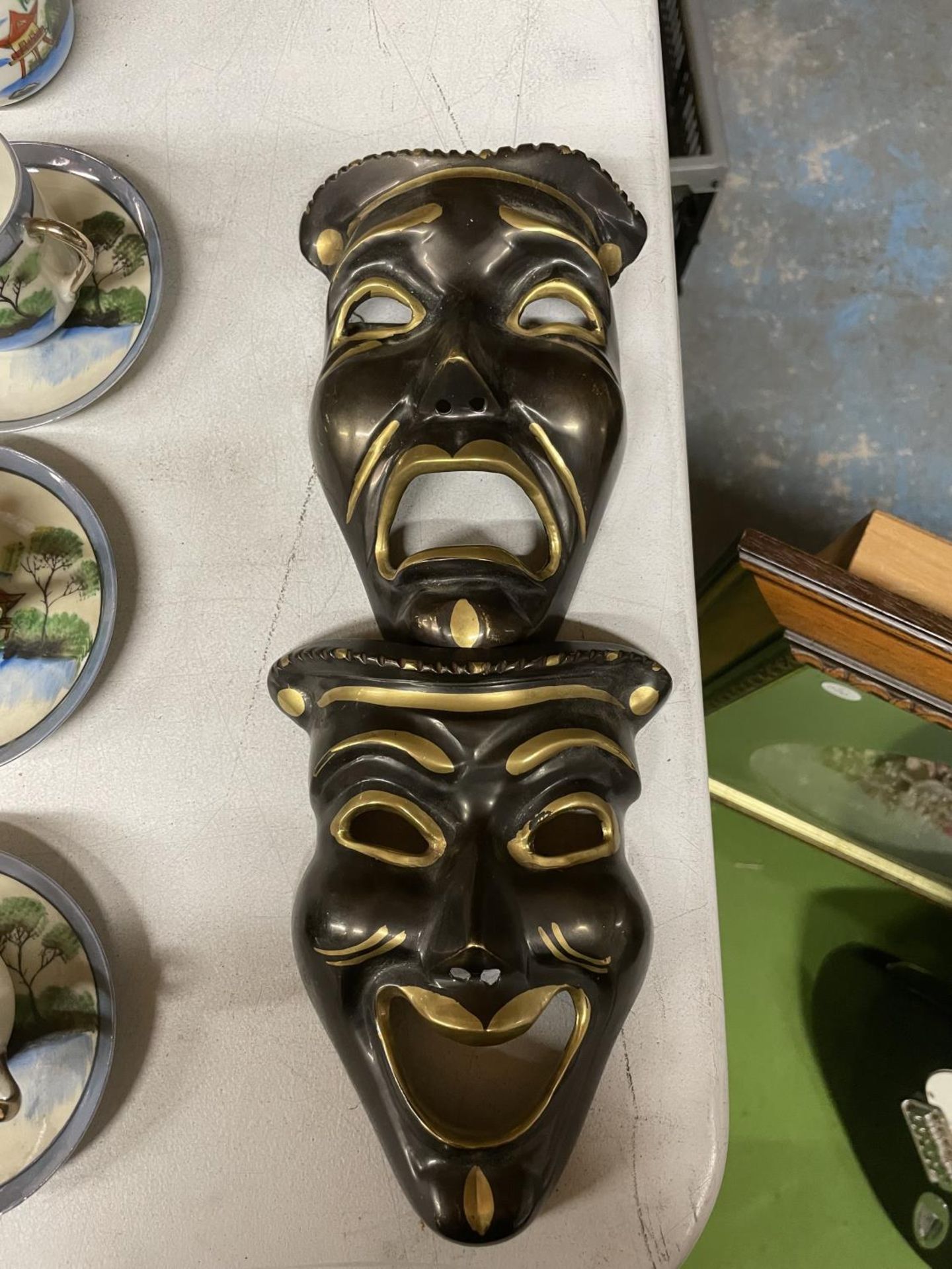 A PAIR OF BLACK AND GOLD COLOURED THEATRICAL COMEDY, TRAGEDY MASKS 17CM X 13CM