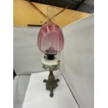 A BRASS OIL LAMP WITH DECORATIVE RESRVOIR, GLASS FUNNEL AND CRANBERRY GLASS SHADE