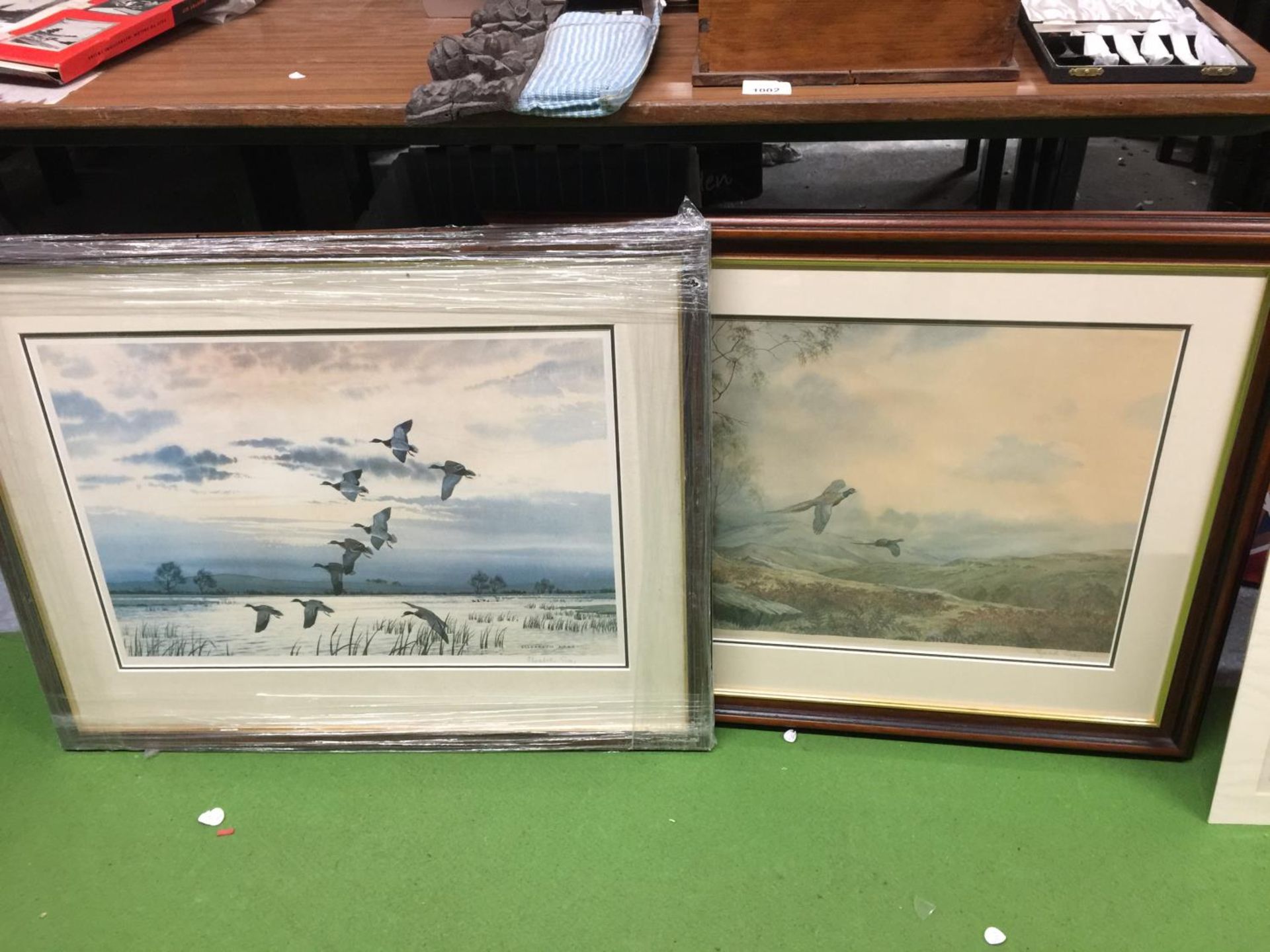 TWO LARGE FRAMED PRINTS SIGNED BY ELIZABETH GRAY, ONE OF DUCKS FLYING OVER WATER, THE OTHER