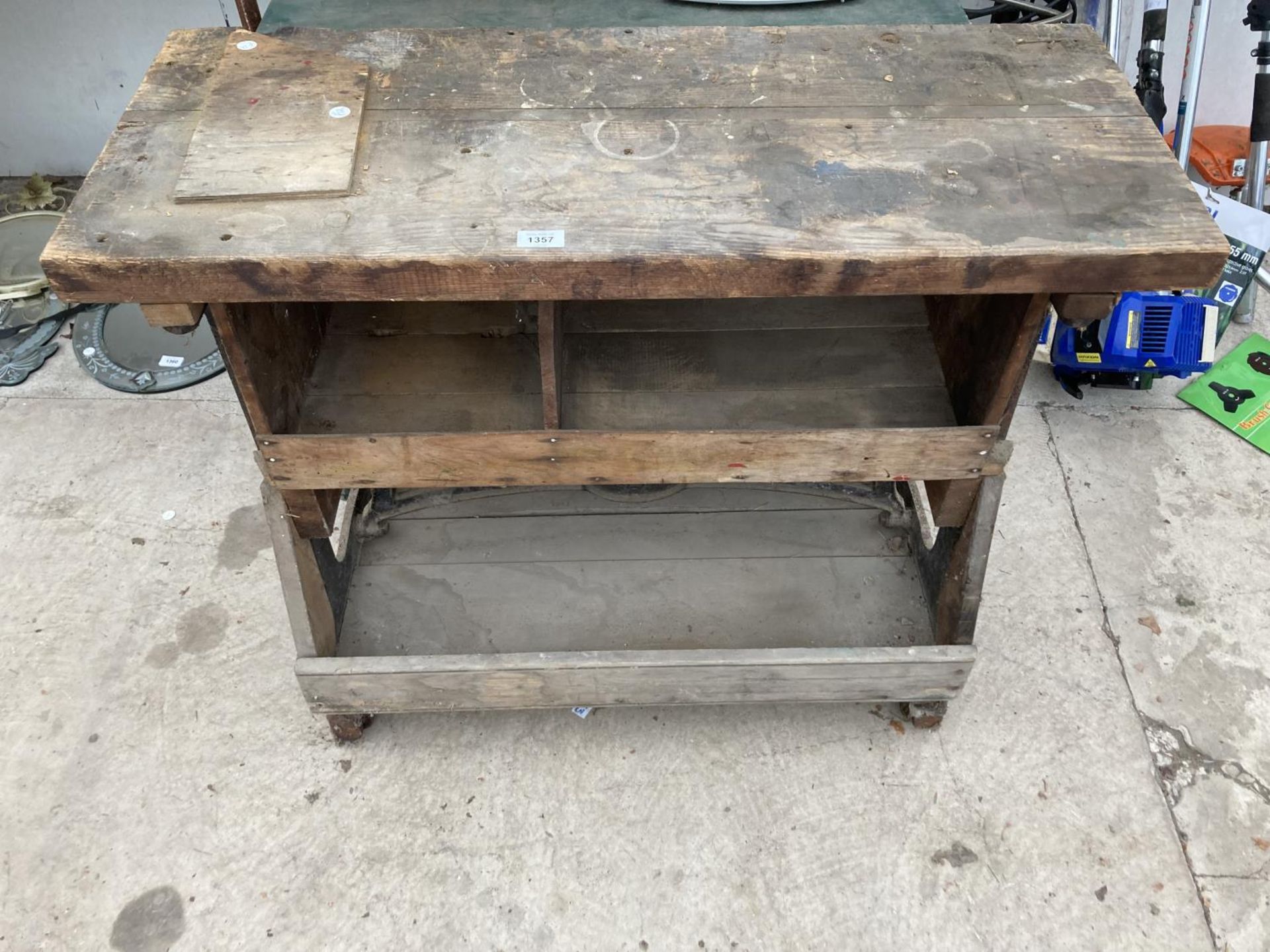 A VINTAGE WOODEN WORK BENCH WITH CAST IRON WHEELED BASE