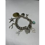 A HEAVY SILVER CHARM BRACELET WITH HEART PADLOCK AND EIGHT CHARMS