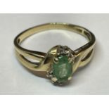A 9 CARAT GOLD RING WITH A SOLITAIRE EMERALD AND TWIST DESIGN TO SHOULDERS SIZE K/L