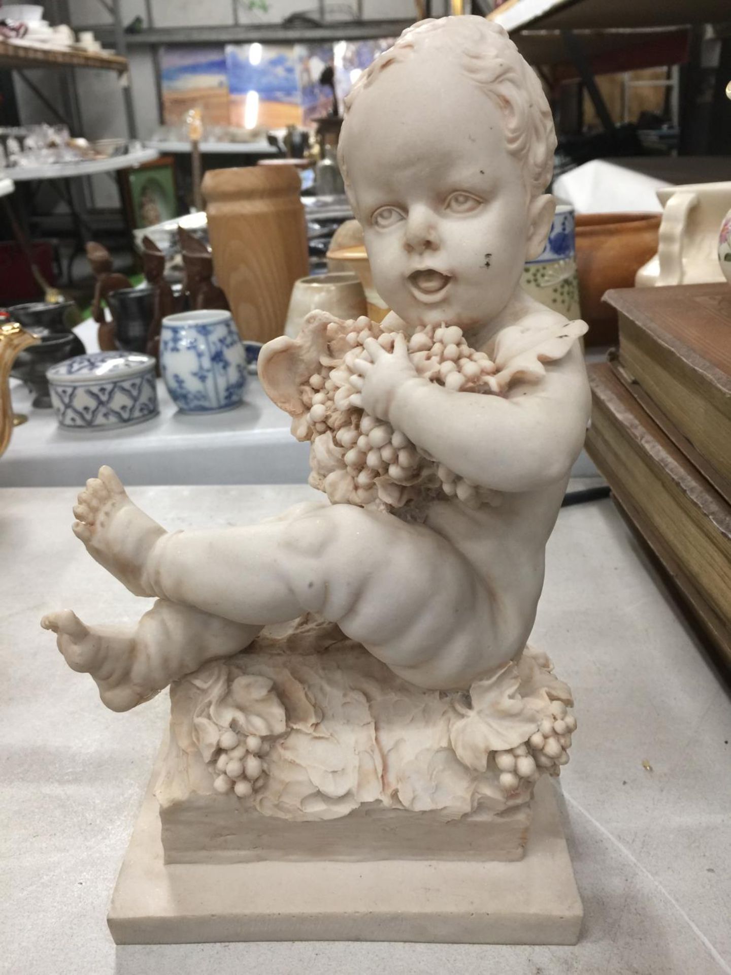 A STATUETTE OF A CHILD WITH GRAPES HEIGHT 26CM