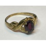 A 9 CARAT GOLD RING WITH TWIST DESIGN SHOULDERS AND A CENTRAL RED STONE SIZE P/Q