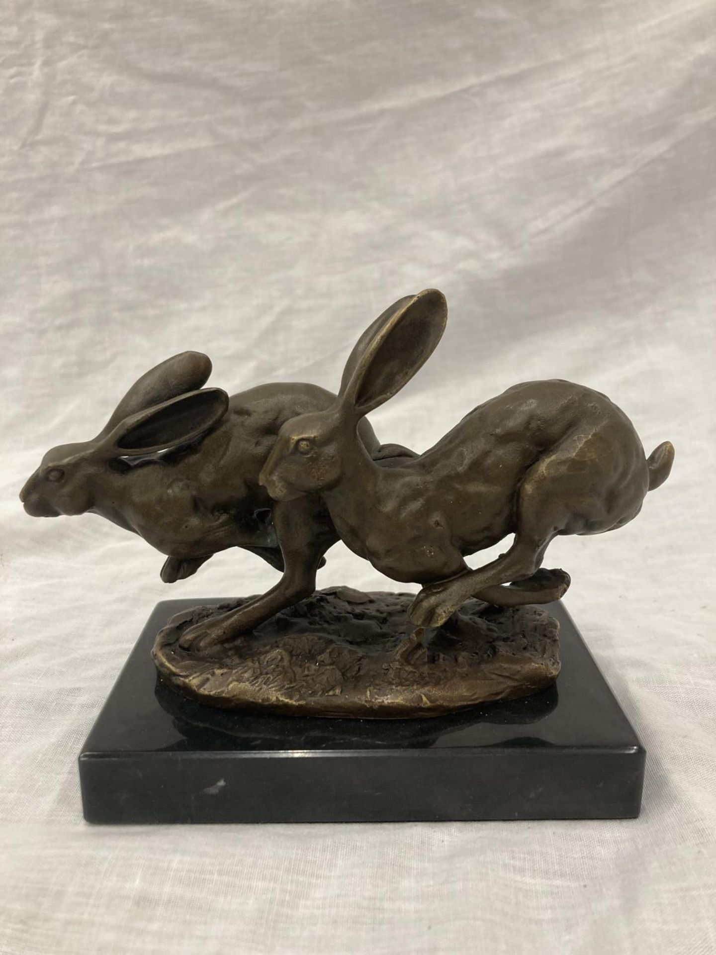 A SIGNED BRONZE OF HARES RUNNING ON A MARBLE PLINTH HEIGHT 12CM, LENGTH 15CM