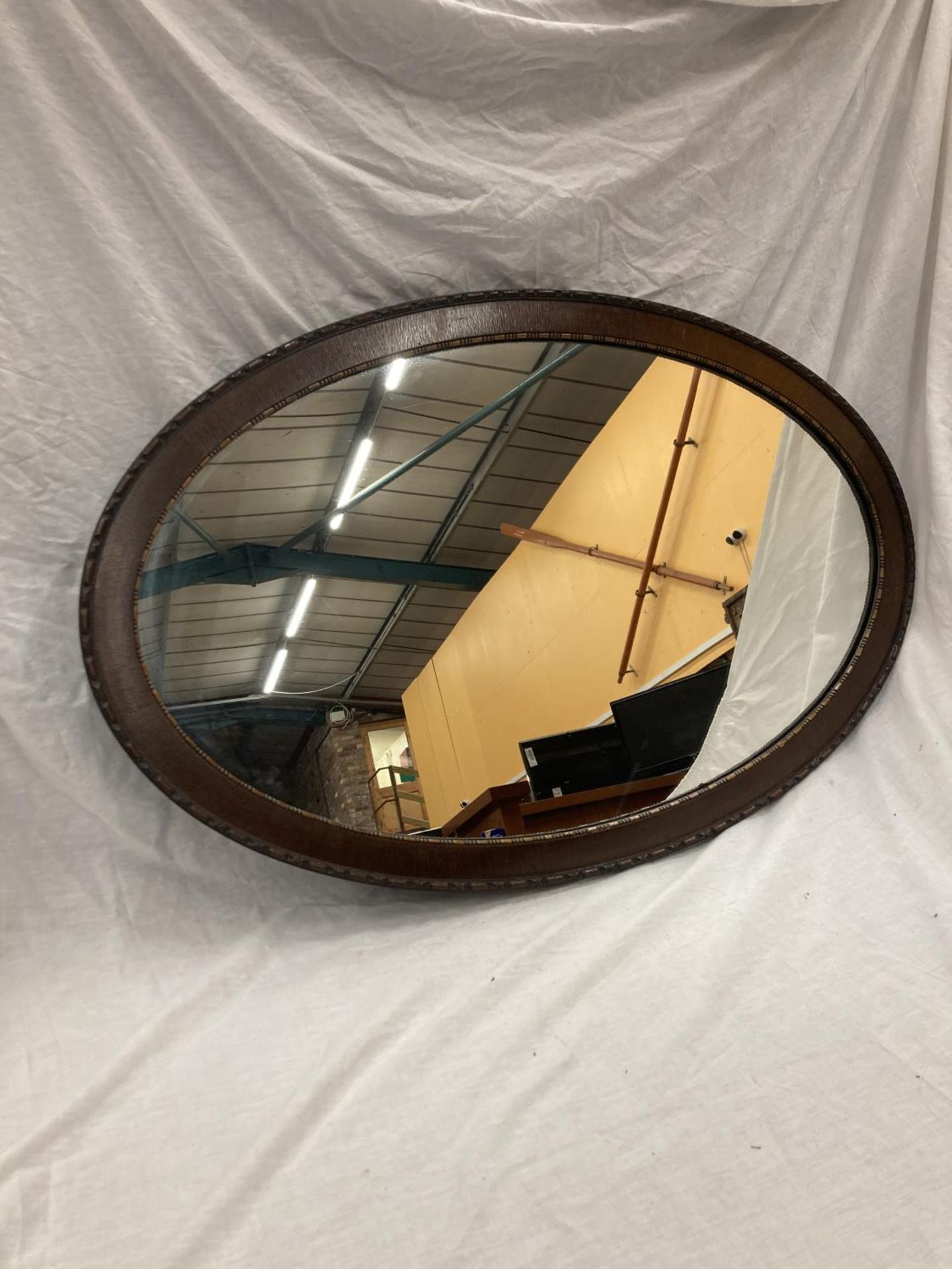 A LARGE MAHOGANY FRAMED OVAL MIRROR WITH BEADED INNER APPROX 100CM X 65CM