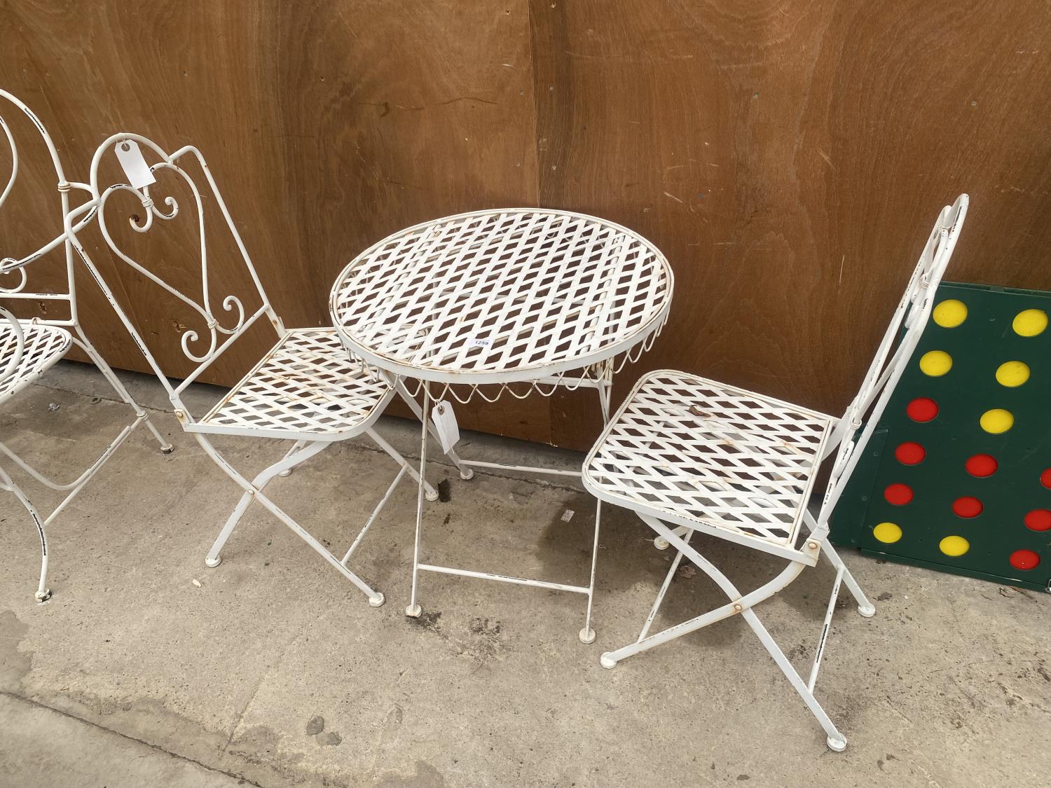 A DECORATIVE WROUGHT IRON BISTRO SET COMPRISING OF A ROUND TABLE AND TWO CHAIRS
