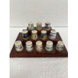 A SET OF TWELVE MINTON BICENTENARY COLLECTION THIMBLES ON A WOODEN STAND