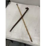 A BAMBOO SWAGGER STICK WITH A WHITE METAL TOP AND A CARVED RIDING CROP WITH A HORSES HEAD HANDLE