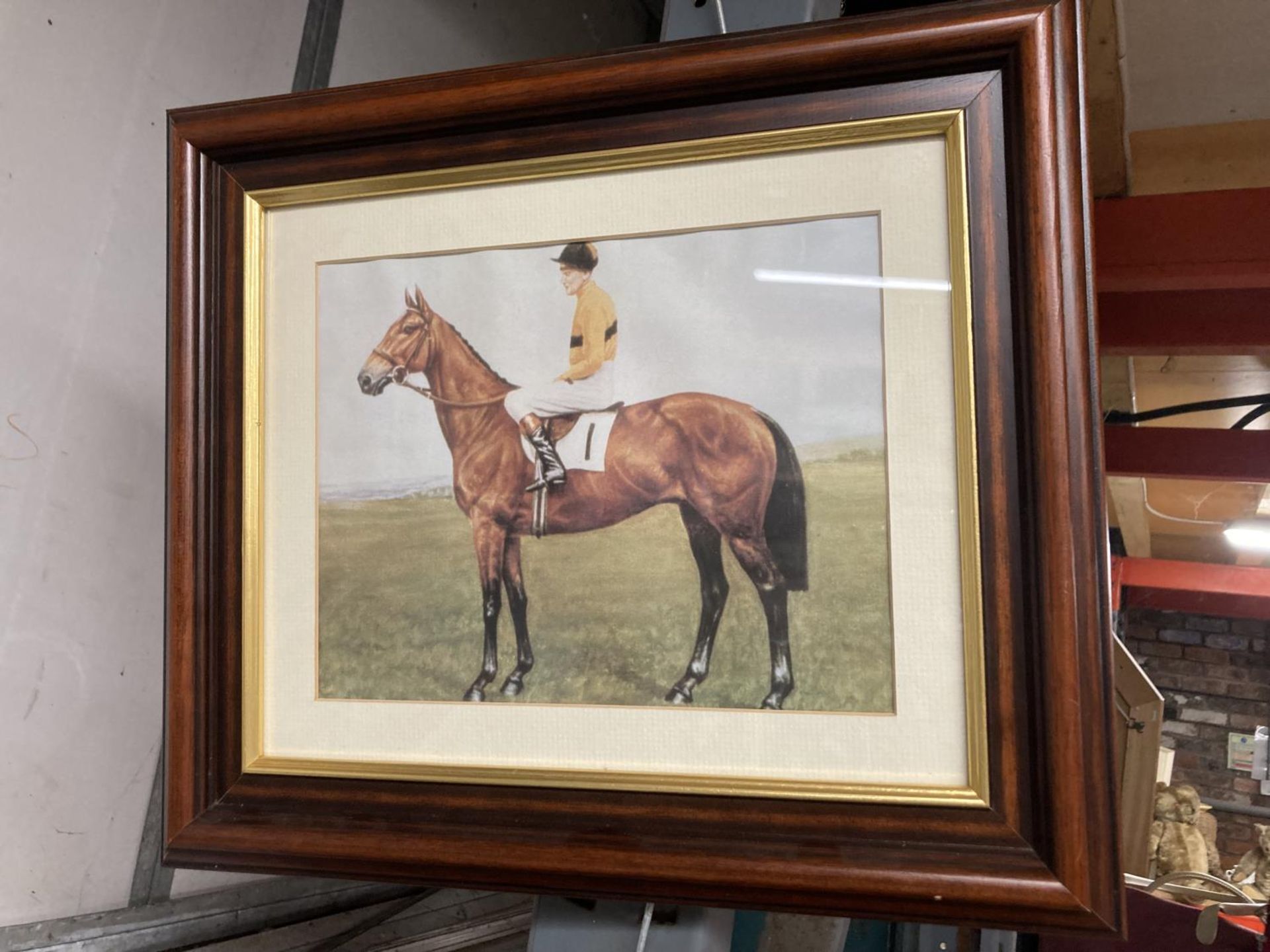 A FRAMED PRINT OF A JOCKEY ON A RACEHORSE (ARKLE?)