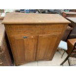 AN EARLY 20TH CENTURY OAK TWO DOOR STORAGE CABINET BEARING DEDICATION TO CHURCH WORKER IN 1943, WITH