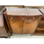 A REGENCY STYLE MAHOGANY BOWFRONTED TWO DOOR SIDE-CABINET WITH APPLIED DECORATION, ON TAPERED LEGS