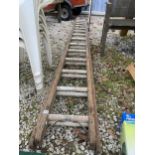 A WOODEN TWO SECTION EXTENDING LADDER WITH 32 METAL RUNGS