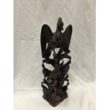 A WOODEN CARVED MODEL OF A LARGE BIRD ON TOP OF OF SMALLER BIRDS HEIGHT 39CM