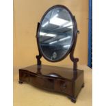 A MAHOGANY OVAL DRESSING TABLE MIRROR WITH A SERPENTINE BOW FRONT CONTAINING ONE LONG AND TWO