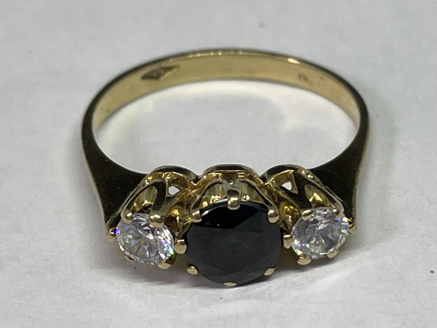 A TESTED TO 9 CARAT GOLD RING WITH CENTRE SAPPHIRE AND A CLEAR STONE EACH SIDE