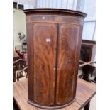 A GEORGE III MAHOGANY BOWFRONTED TWO DOOR CORNER CUPBOARD