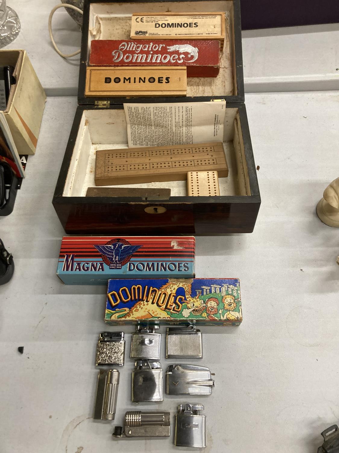 A MAHOGANY BOX CONTAINING VINTAGE DOMINOES AND CRIBBAGE BOARDS PLUS A QUANTITY OF VINTAGE LIGHTERS