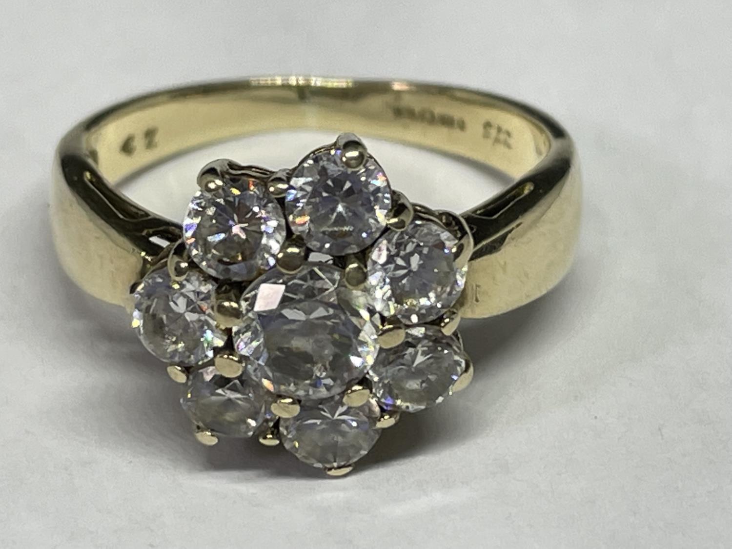 A 9 CARAT GOLD RING WITH EIGHT CUBIC ZIRCONIA STONES IN A FLOWER DESIGN SIZE O