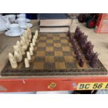 A CARVED WOODEN CHESS BOARD WITH A FULL SET OF CHESSMEN