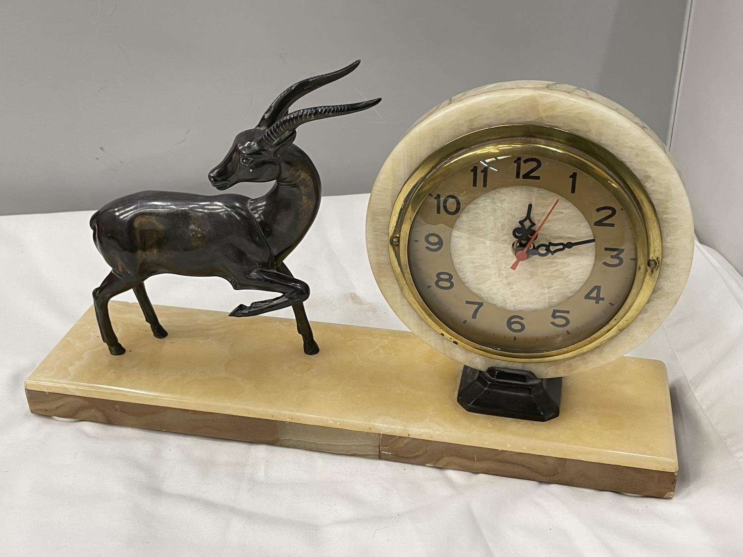 A MARBLE CIRCULAR CLOCK ON A MARBLE BASE WITH A METAL GAZELLE DECORATION BASE 40CM X 10CM