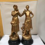 A GOLD COLOURED FIGURE OF A WOMAN ON A PLINTH HEIGHT 51CM PLUS A GOLD COLOURED FIGURE OF A MAN ON