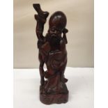 A WOODEN CARVING OF AN ORIENTAL FIGURE HEIGHT 31CM