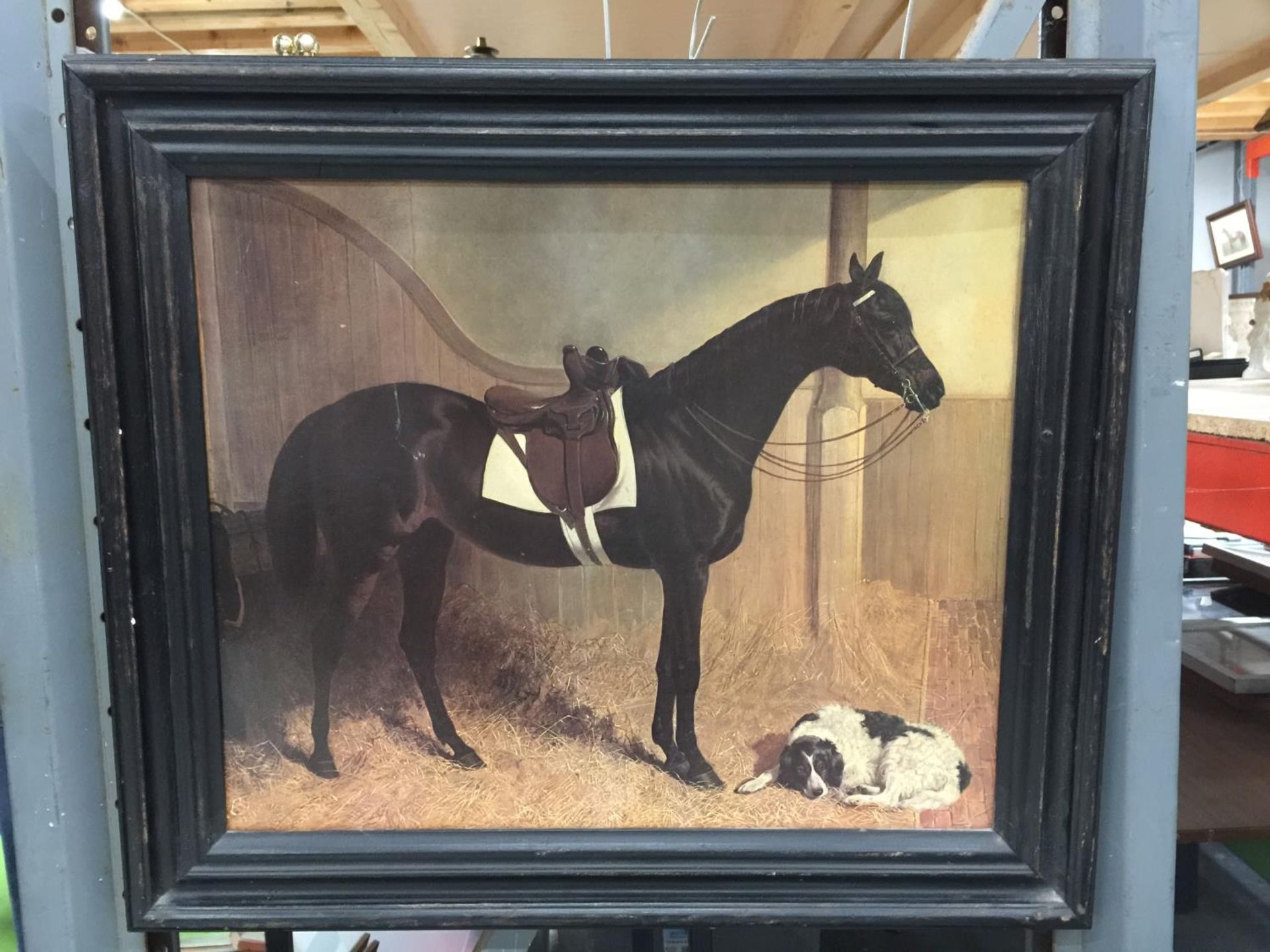 A DARK FRAMED PRINT OF A HORSE AND A DOG IN A STABLE