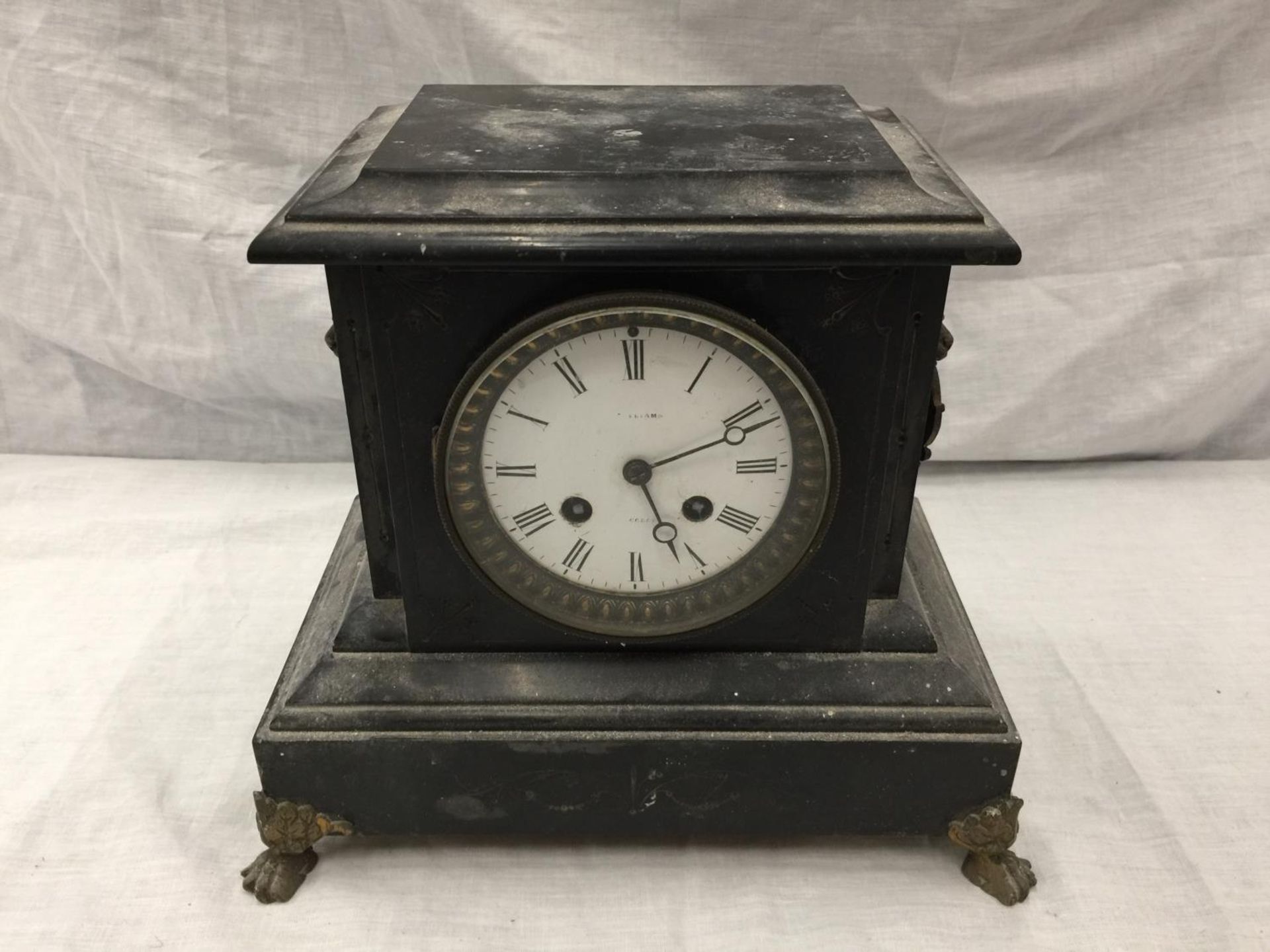 A HEAVY VINTAGE MANTEL CLOCK WITH BRASS DECORATION AND CLAW FEET