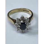 A 9 CARAT GOLD RING WITH A CENTRE SAPPHIRE SURROUNDED BY EIGHT DIAMONDS SIZE H