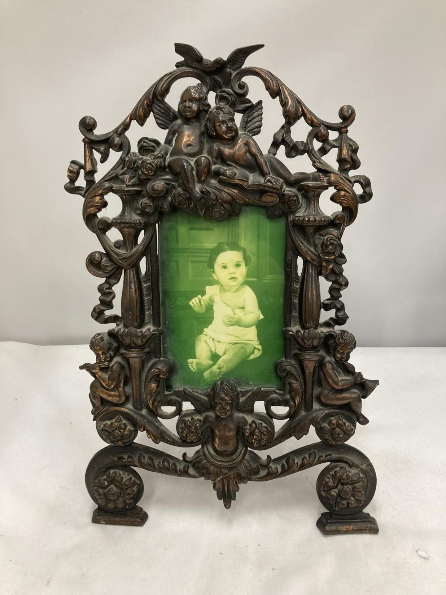 A METAL PHOTO FRAME DECORATED WITH SWAGS AND CHERUBS HEIGHT 35CM, WIDTH 23CM - A/F