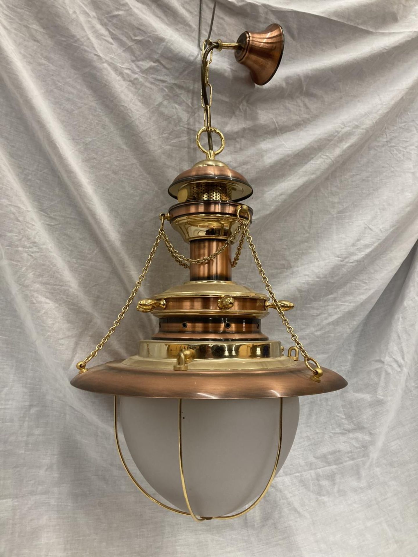 AN UNUSUAL BRASS AND COPPER PENDANT LIGHT WITH DOMED GLASS SHADE, SHIPS WHEEL DESIGN AND CHAINS