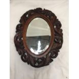 AN CARVED OAK FRAMED OVAL MIRROR WITH BEVELLED GLASS 39CM X 30CM