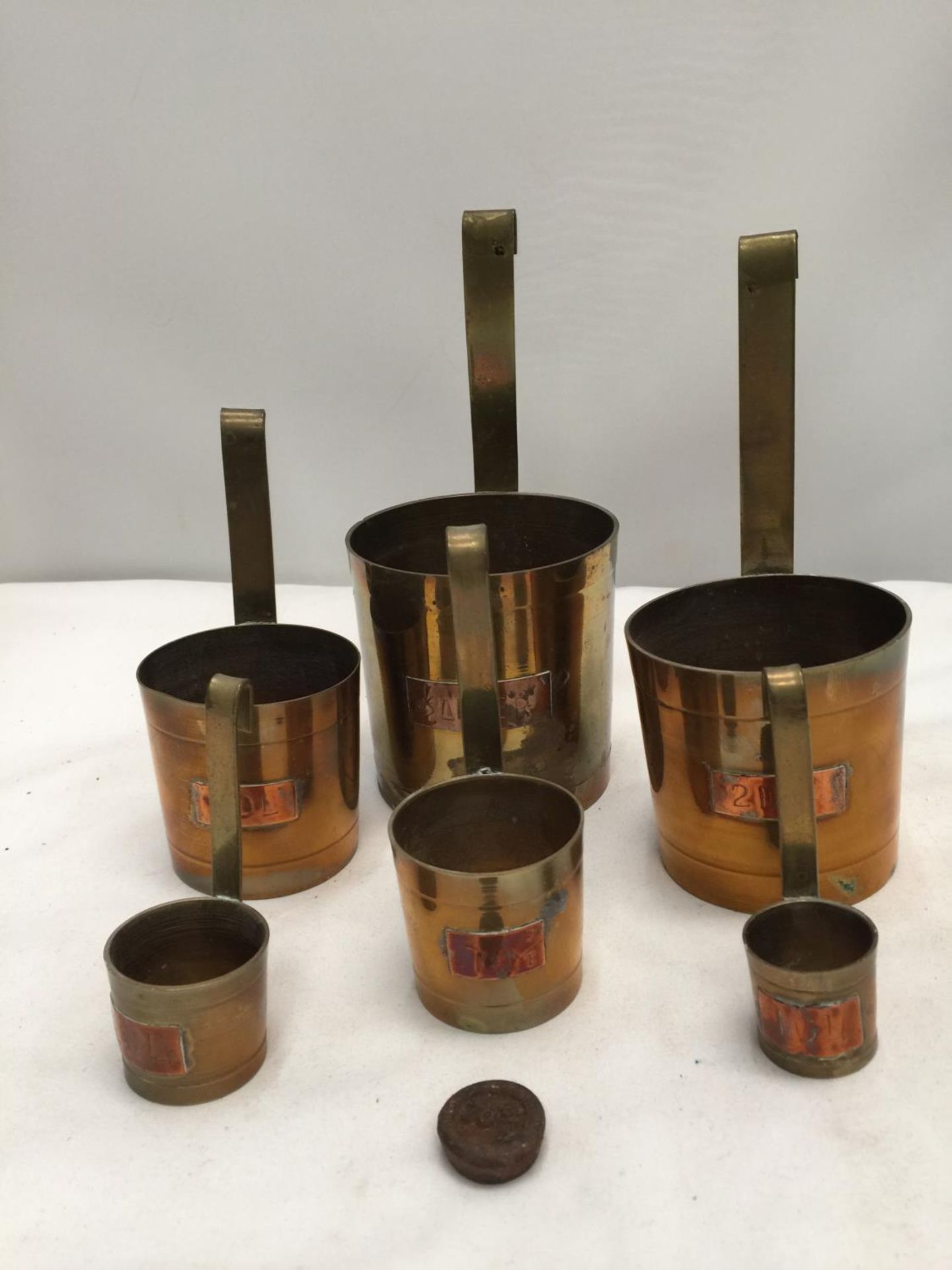 SIX GRADUATED COPPER AND BRASS SPIRIT MEASURES