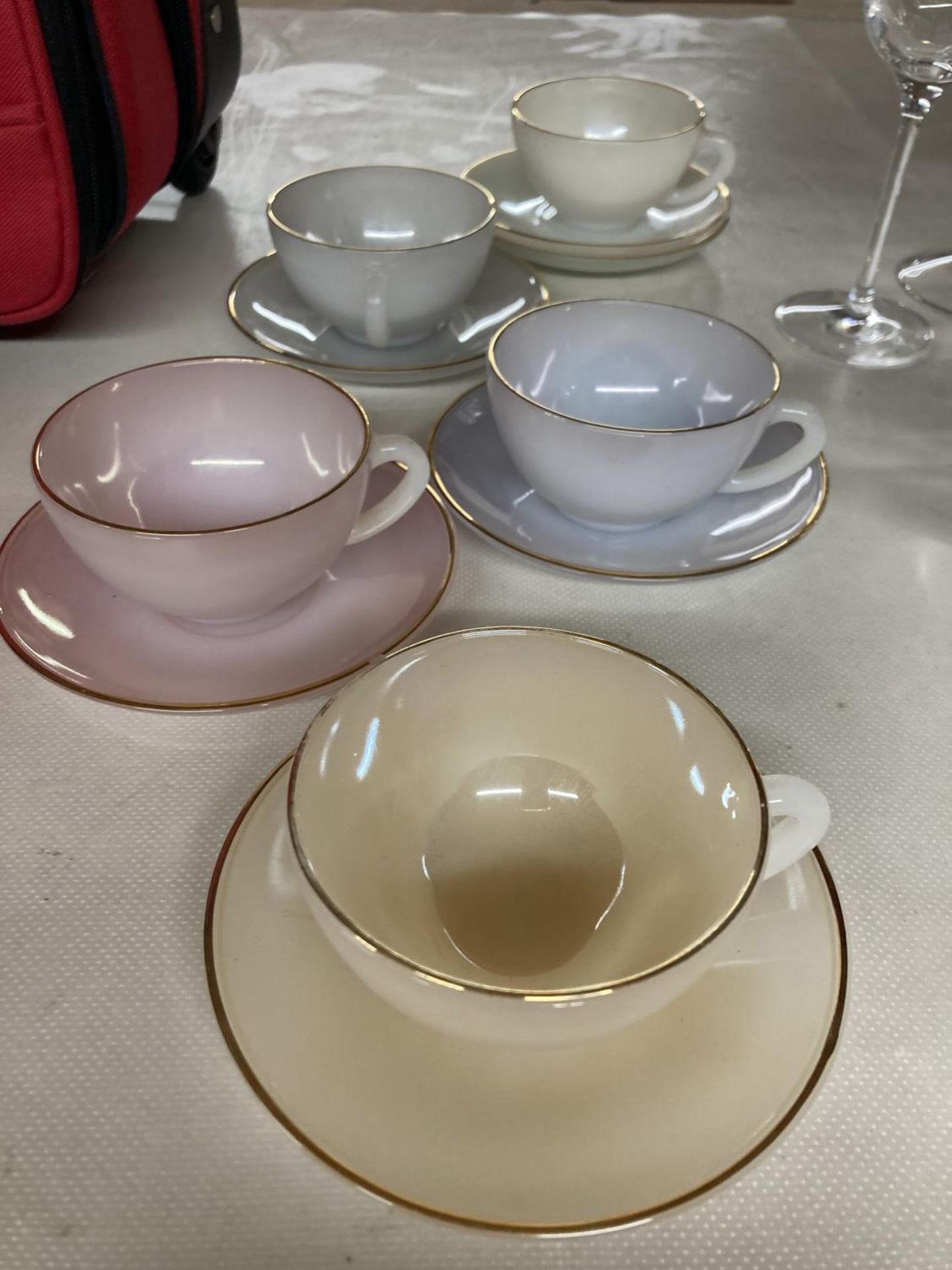 A COLLECTION OF ARCOPAL CUPS AND SAUCERS IN PASTEL SHADES