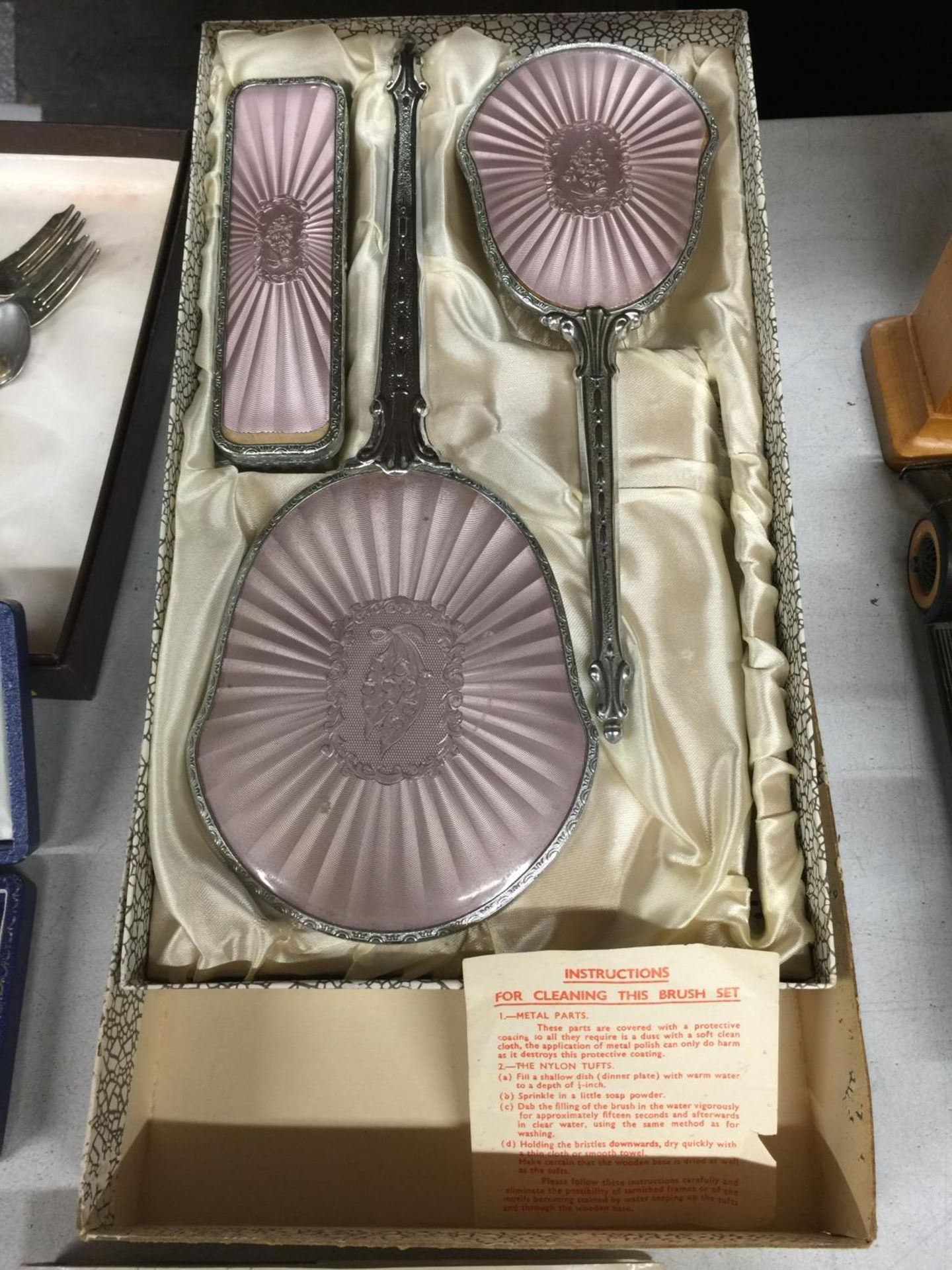 A BOXED BRUSH AND MIRROR SET WITH PINK CUSHIONED BACK