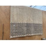 A MODERN BEIGE WOVEN RUG