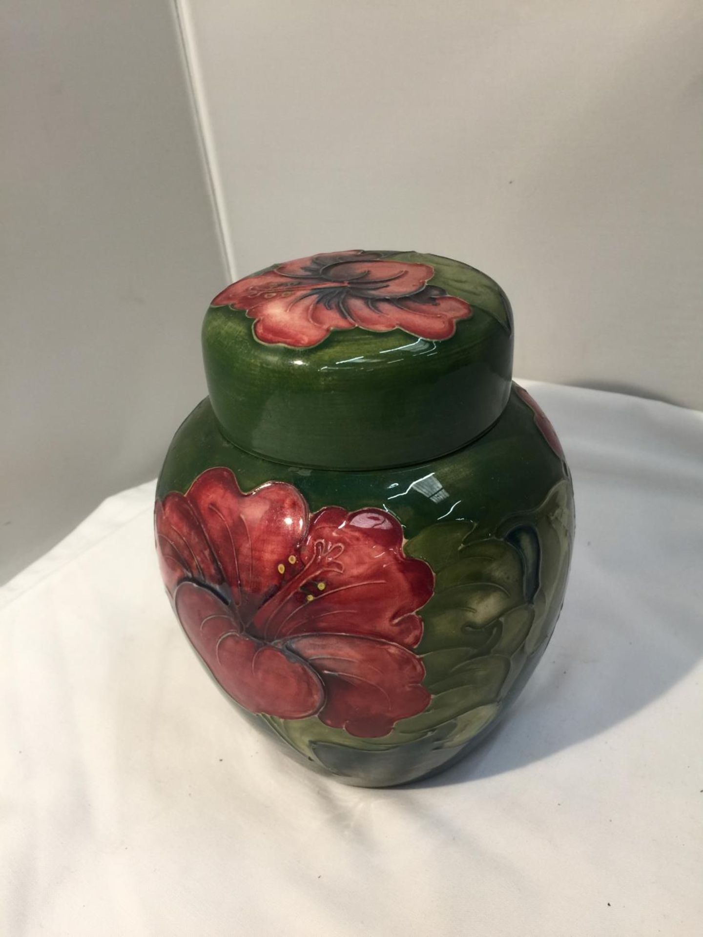 A MOORCROFT HIBISCUS ON GREEN GINGER JAR