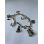 A SILVER CHARM BRACELET WITH SEVEN VARIOUS CHARMS