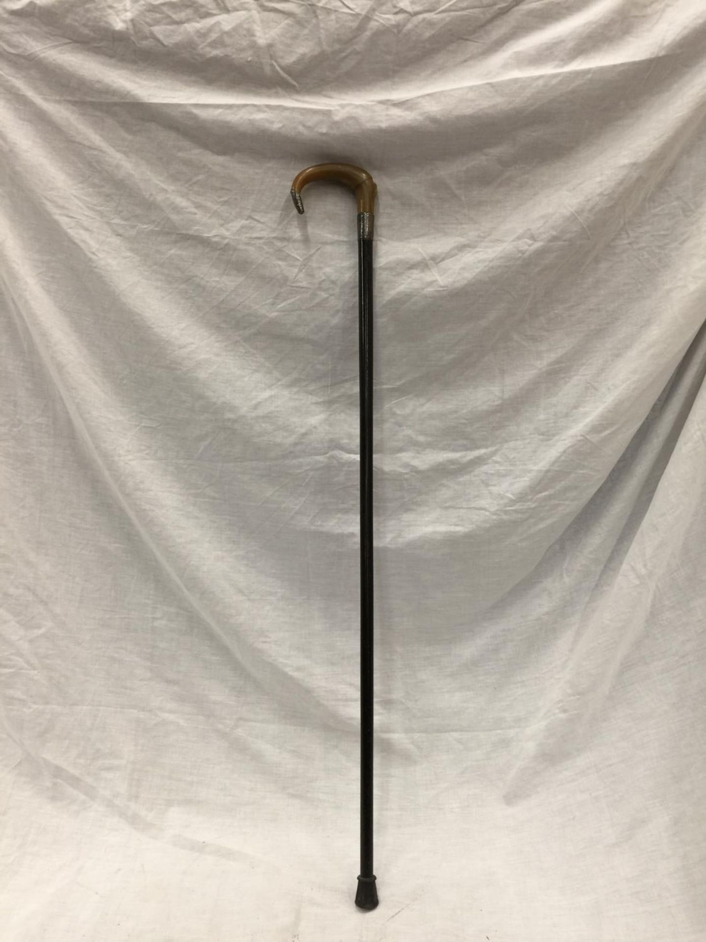 A WALKING CANE WITH SILVER BAND AND A HORN HANDLE